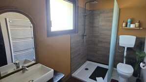 Ein modernes Badezimmer mit großem Spiegel, Waschbecken, Dusche und Toilette.