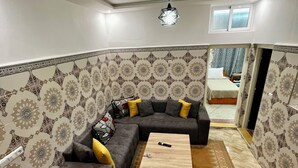 Ein modernes Wohnzimmer mit einer Eckcouch, einem Couchtisch aus Holz und Wandtapete mit Muster.
