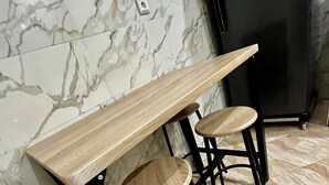 Eine Küche mit Marmorfliesenspiegel, einem schwarzen Kühlschrank und einem Holztisch mit zwei Barhocker.