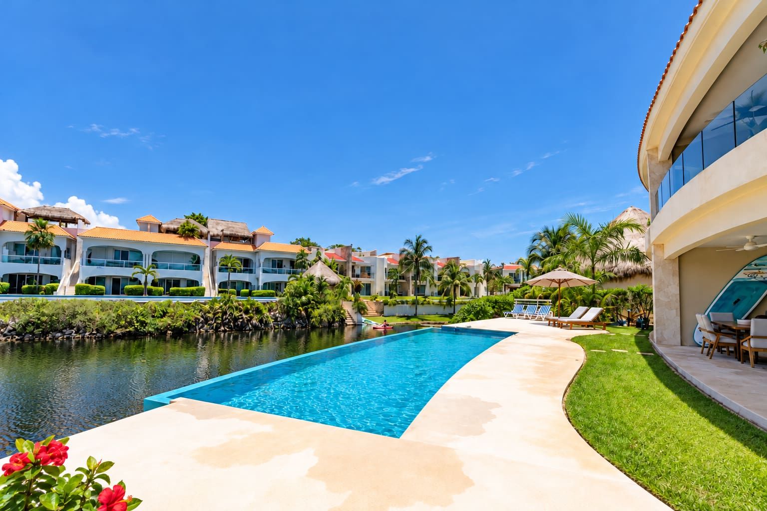 A resort pool area with a clear blue pool, lounge chairs, and a palm tree-lined walkway.