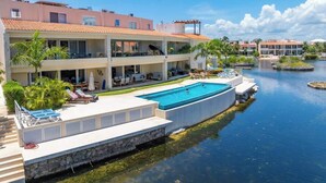 Et resort med en stor swimmingpool, flere balkoner og udsigt over vandet.