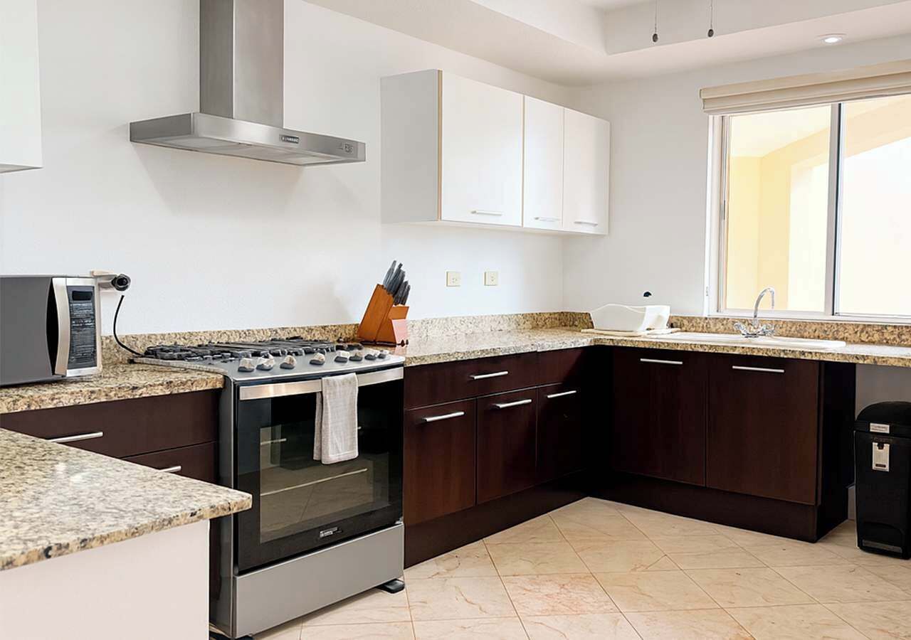 A modern kitchen with dark wooden cabinets, a stainless steel range, and a granite countertop.
