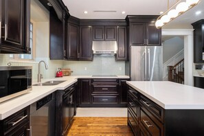 A modern kitchen with dark cabinetry, stainless steel appliances, and a white countertop.