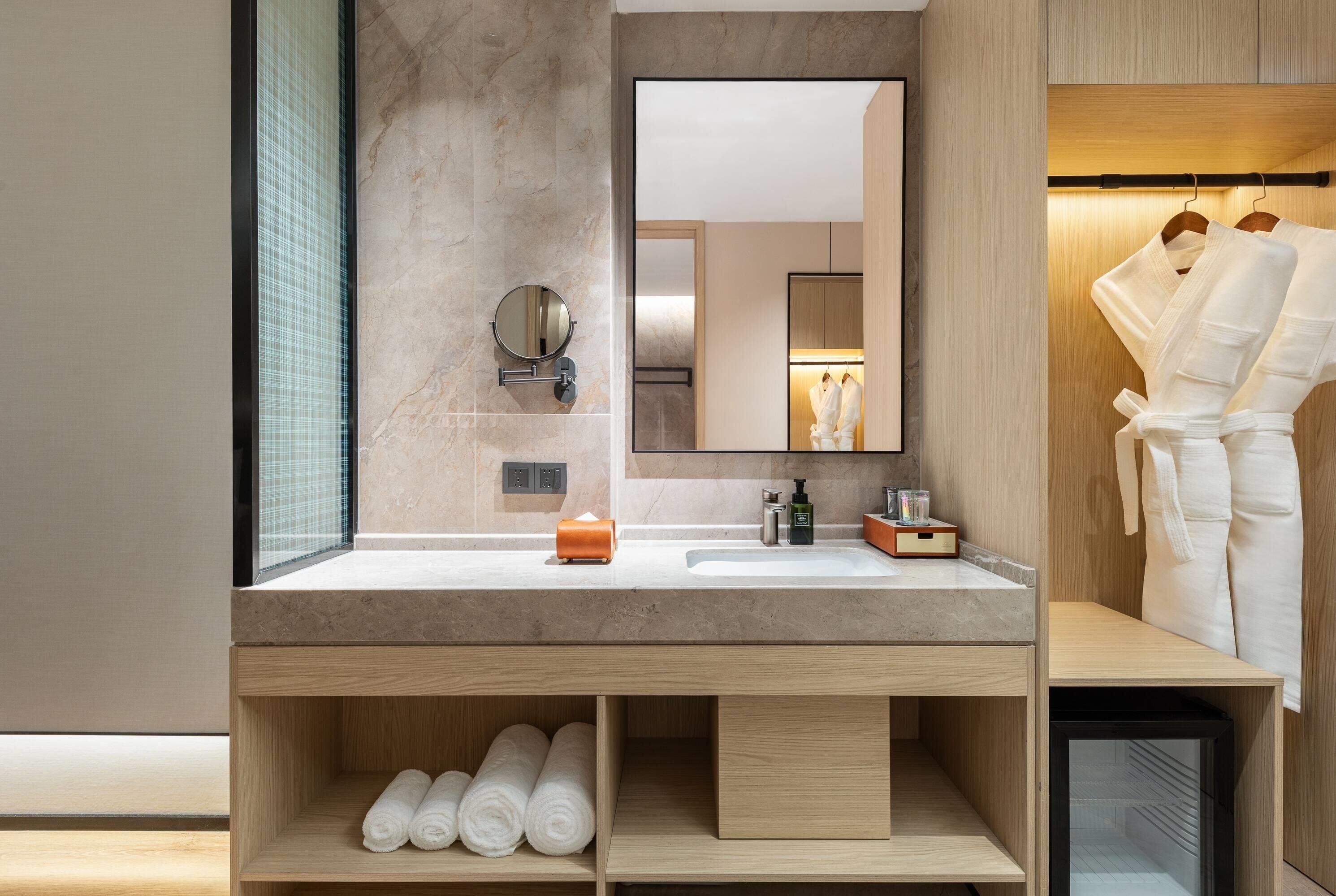 Une salle de bain moderne avec un lavabo en marbre, un miroir et un meuble de rangement intégré contenant des serviettes.