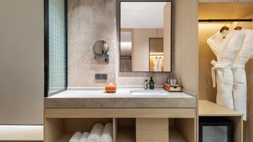 Une salle de bain moderne avec un lavabo en marbre, un miroir et un meuble de rangement intégré contenant des serviettes.
