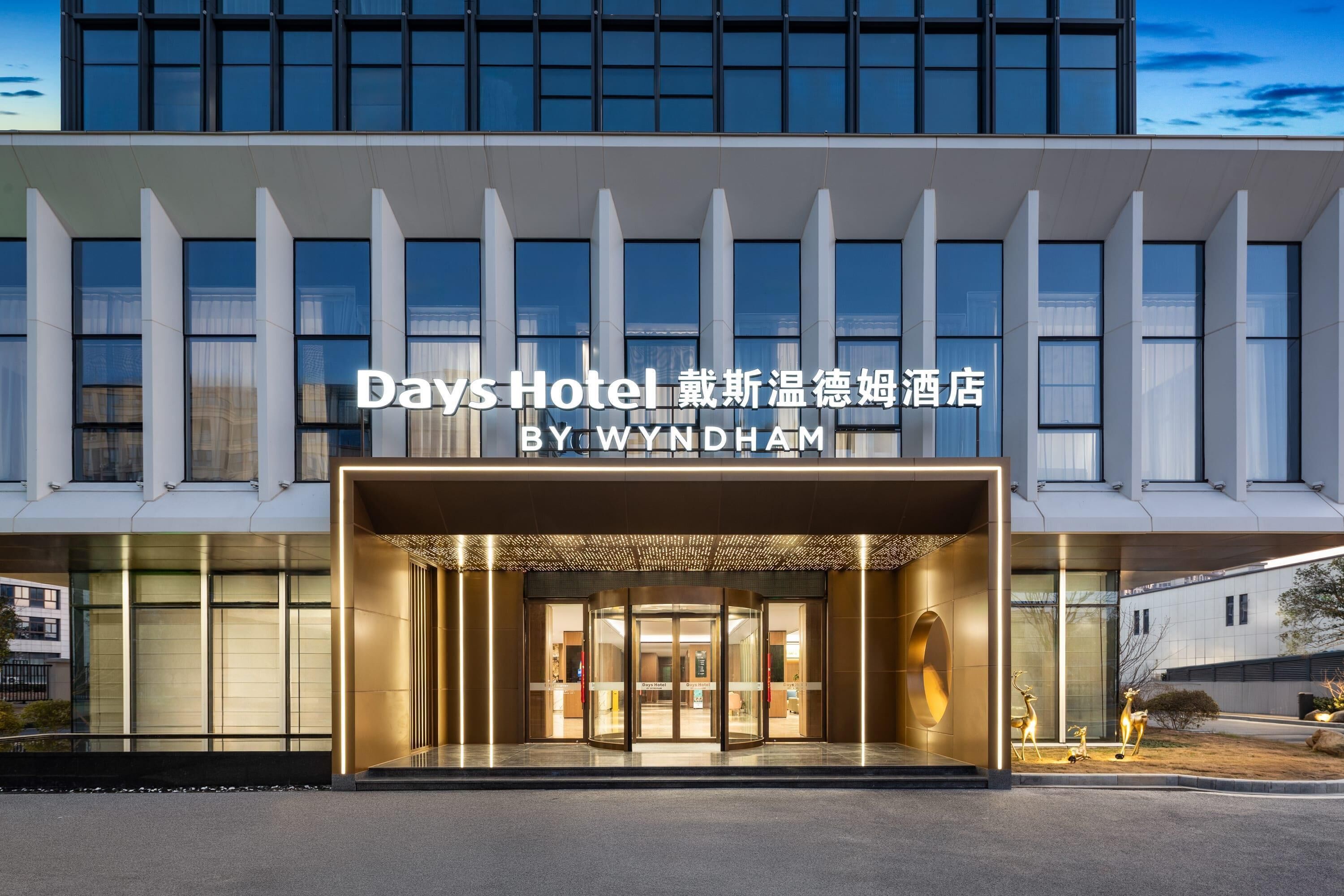 The exterior of Days Hotel with a modern design, featuring a glass entrance and a sign indicating it is by Wyndham.