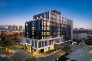 A modern hotel with a glass facade, a visible entrance, and a parking area. - Days Hotel By Wyndham Huzhou Anji (Huzhou)