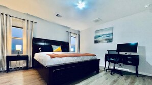 Ein Schlafzimmer mit Bett, Schreibtisch, Fernseher und einem Bild an der Wand.