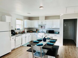 A modern kitchen with white cabinets, a granite countertop, and a dining area with a table set for four.