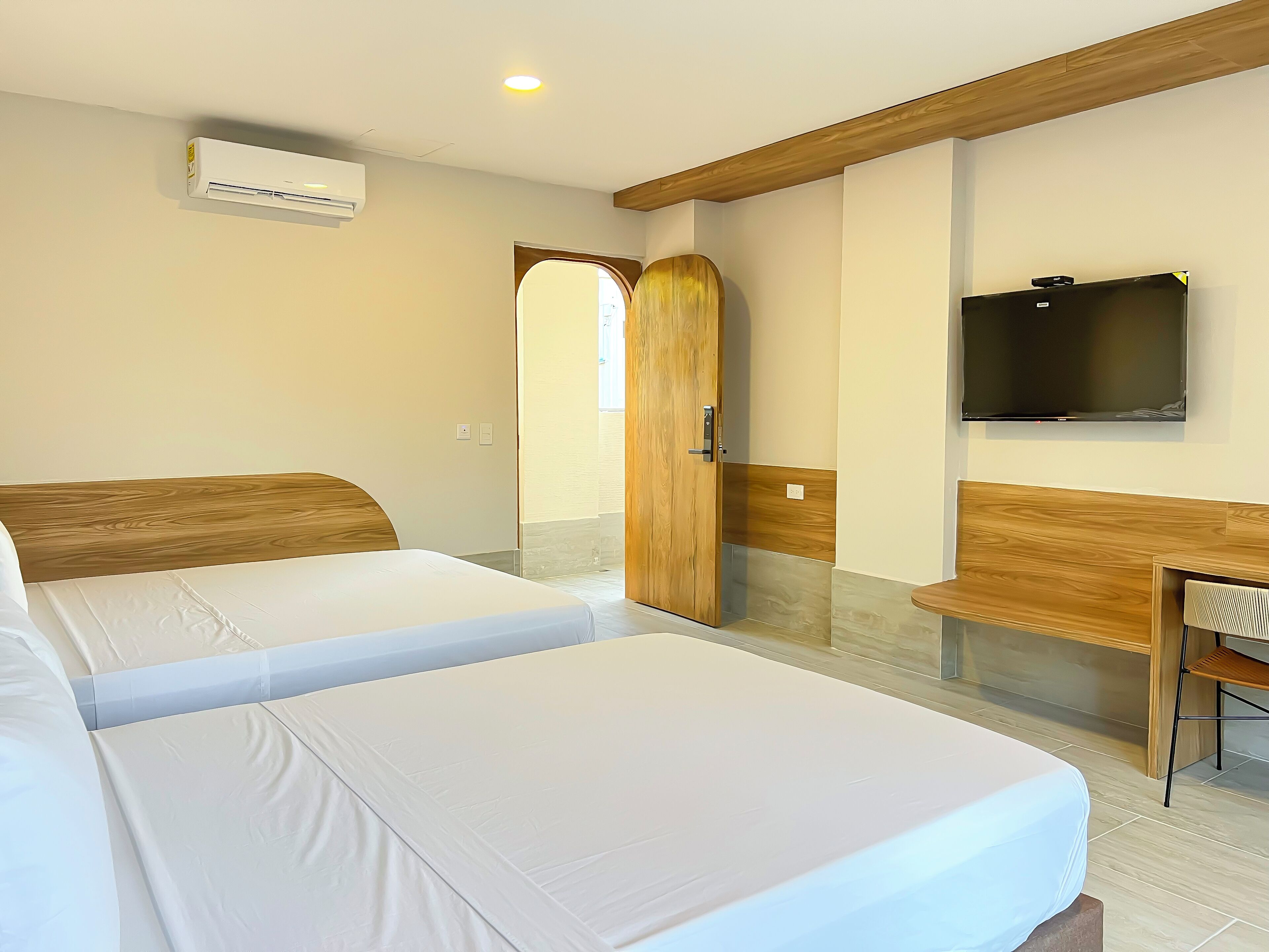Habitación de hotel con dos camas, un televisor y una puerta de madera.