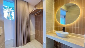 Une salle de bain moderne avec un grand miroir, un lavabo blanc et un porte-serviettes.