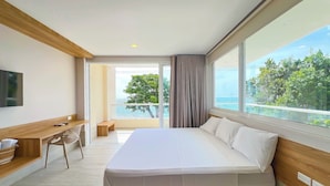 Une chambre d’hôtel moderne avec un grand lit, un bureau et une vue sur la mer.