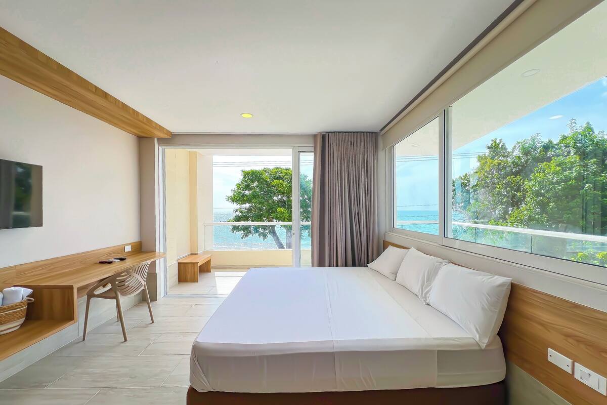 Une chambre d’hôtel moderne avec un grand lit, un bureau et une vue sur la mer.