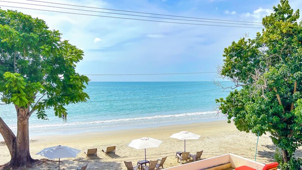 Une vue sur la plage avec un espace piscine, des chaises longues et des parasols.
