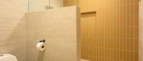 A modern bathroom with a toilet, a glass shower enclosure, and a toilet paper holder.
