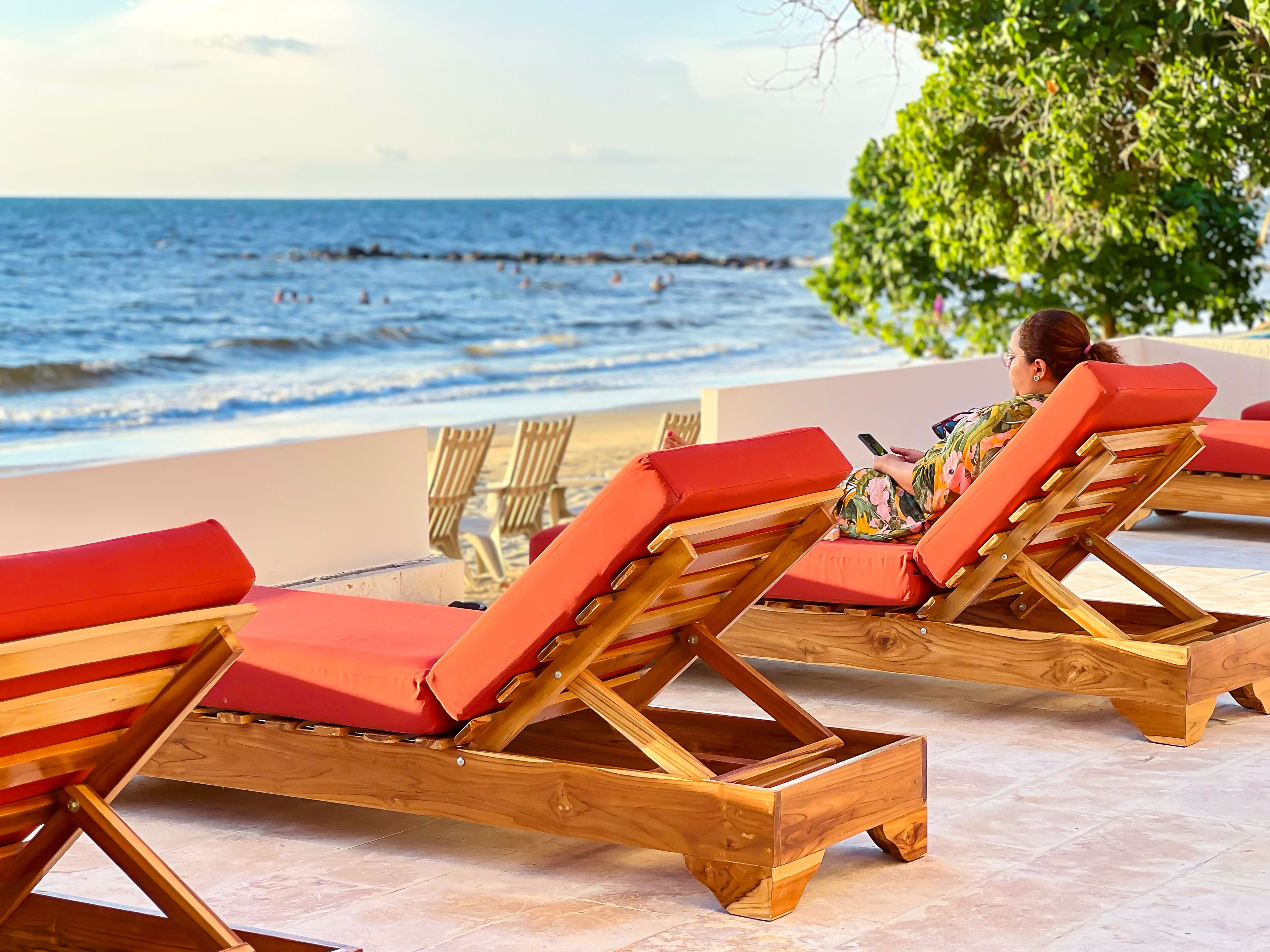Un área de descanso frente a la playa con sillones de madera y vista al océano.