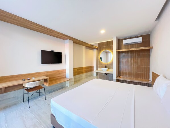 A modern hotel room with a large bed, a desk with a chair, a flat-screen TV, a round mirror with lighting, and a wardrobe. - Hotel Stanza del Mar (Coveñas)