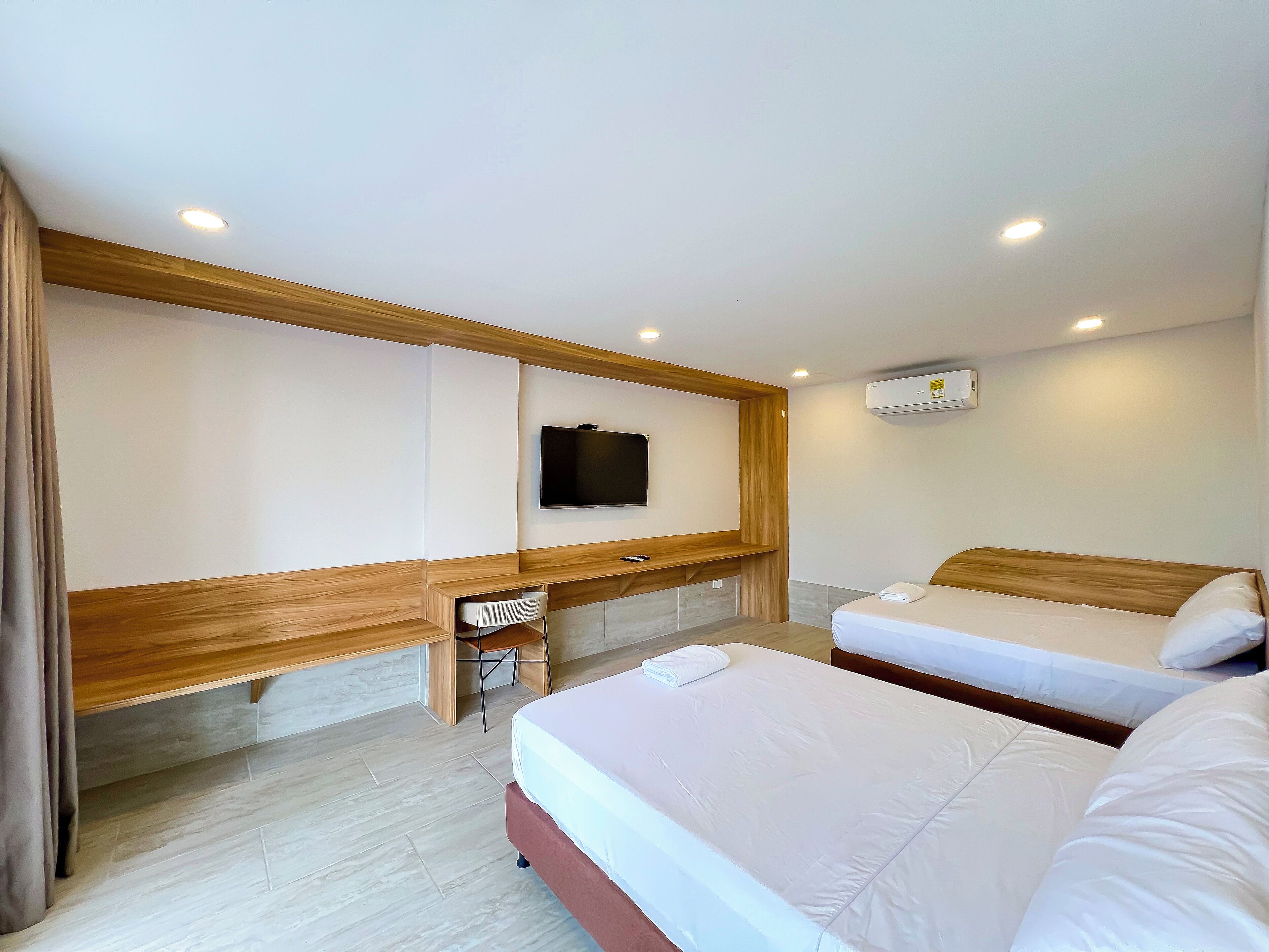 Une chambre d’hôtel avec deux lits, un téléviseur fixé au mur et un bureau avec une chaise.