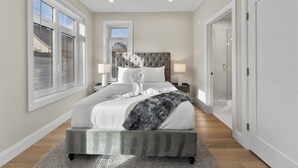 A bedroom with a large bed, a tufted headboard, bedside lamps, and a view through a door. - Luxury 2bd/2ba near Cabmridge 64fp (Somerville)