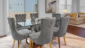 A dining area with a glass table and grey upholstered chairs, a living room with a sofa and cushions, and a large abstract painting on the wall. - 3 King Bdrs - Modern Fully Equipped Upscale House (Charlotte)