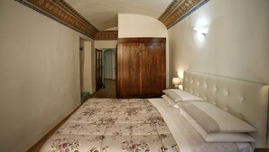 A bedroom with a bed, a wooden wardrobe, and a light fixture on the wall. - Il Terrazzino (Cetona)