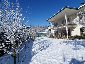 Een besneeuwde woonwijk met huizen, een heldere lucht en een groene zeil op de grond.