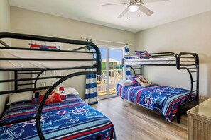 Ein Zimmer mit zwei Etagenbetten, einem Deckenventilator und Blick auf einen Balkon.