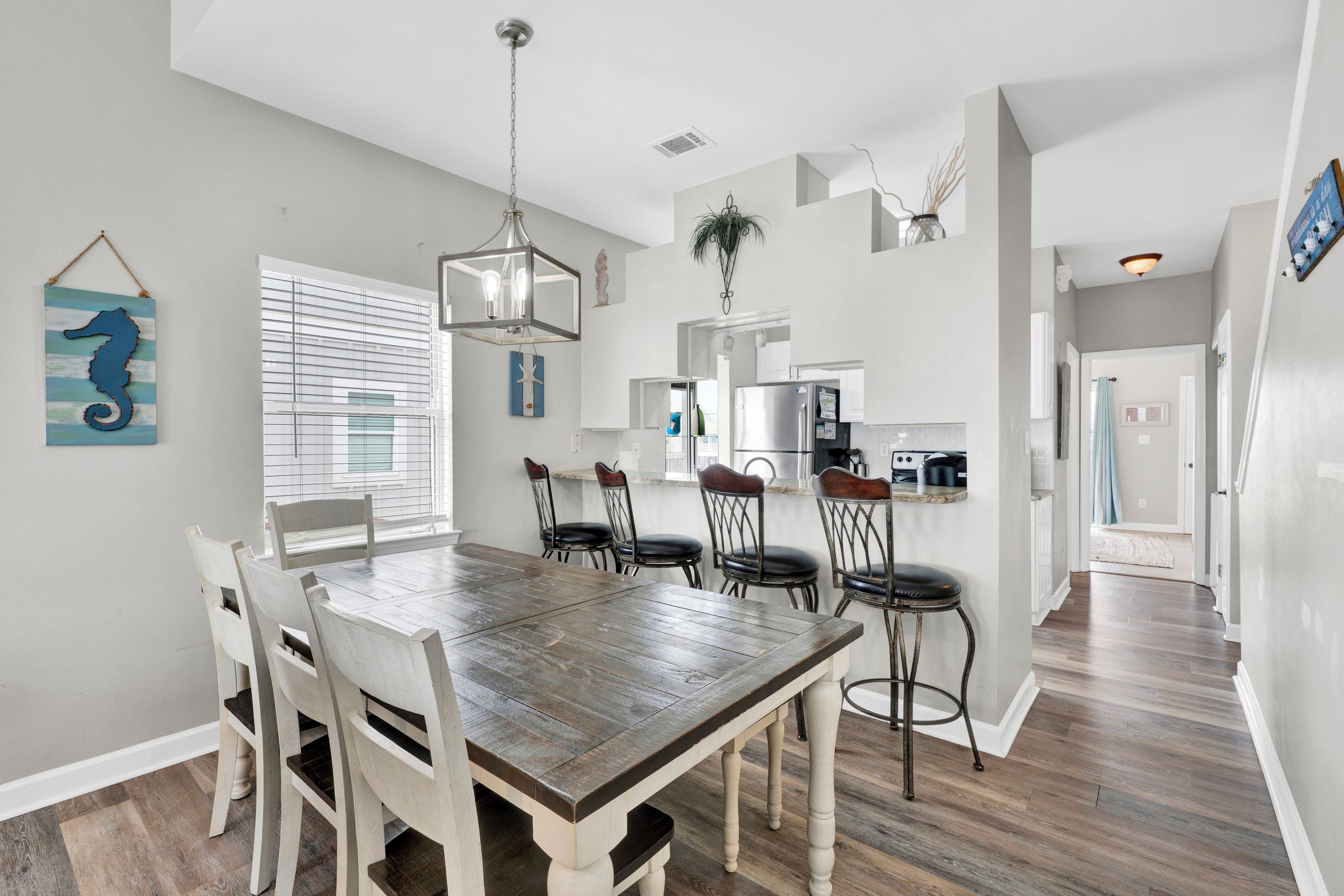 Un'area pranzo con un tavolo e sedie in legno, un lampadario e vista sulla cucina.