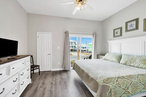 Une chambre à coucher comprenant un lit, une commode, un téléviseur et un ventilateur de plafond.