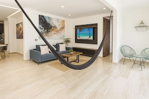 Ein modernes Wohnzimmer mit einer Hängematte, einem Sofa, einem Couchtisch und einem Fernseher.