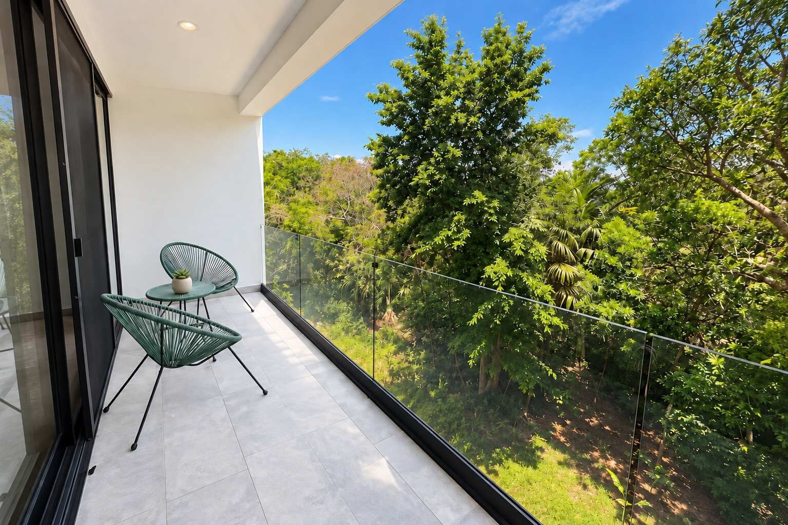 Ein Balkon mit zwei Stühlen und einem Tisch, der auf eine üppige, grüne Landschaft blickt.