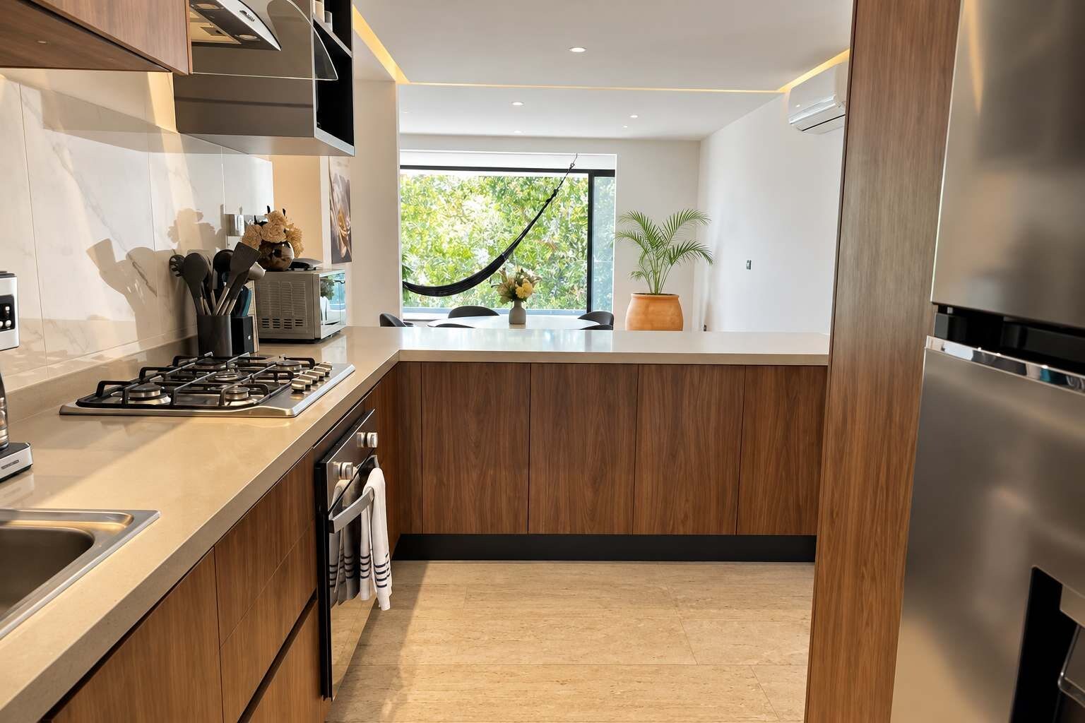 Une cuisine moderne dotée d’un îlot central, d’appareils électroménagers en acier inoxydable et offrant une vue sur la verdure environnante.