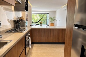Una cuina moderna amb una illa central, electrodomèstics d'acer inoxidable i vistes a vegetació exterior.