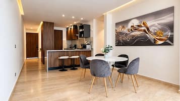 Una cocina moderna con una isla central, un comedor con mesa y sillas redondas, y un cuadro abstracto grande en la pared.