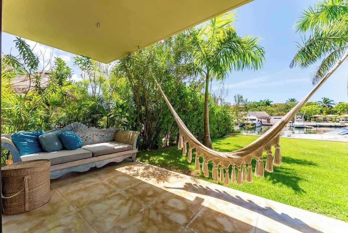 Un hamac sur une terrasse, avec vue sur un jardin luxuriant et une piscine.