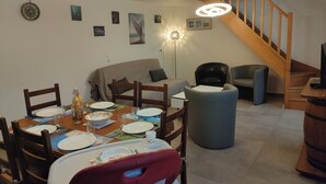 Un comedor con una mesa redonda para cuatro personas, un sofá, una silla y una escalera.