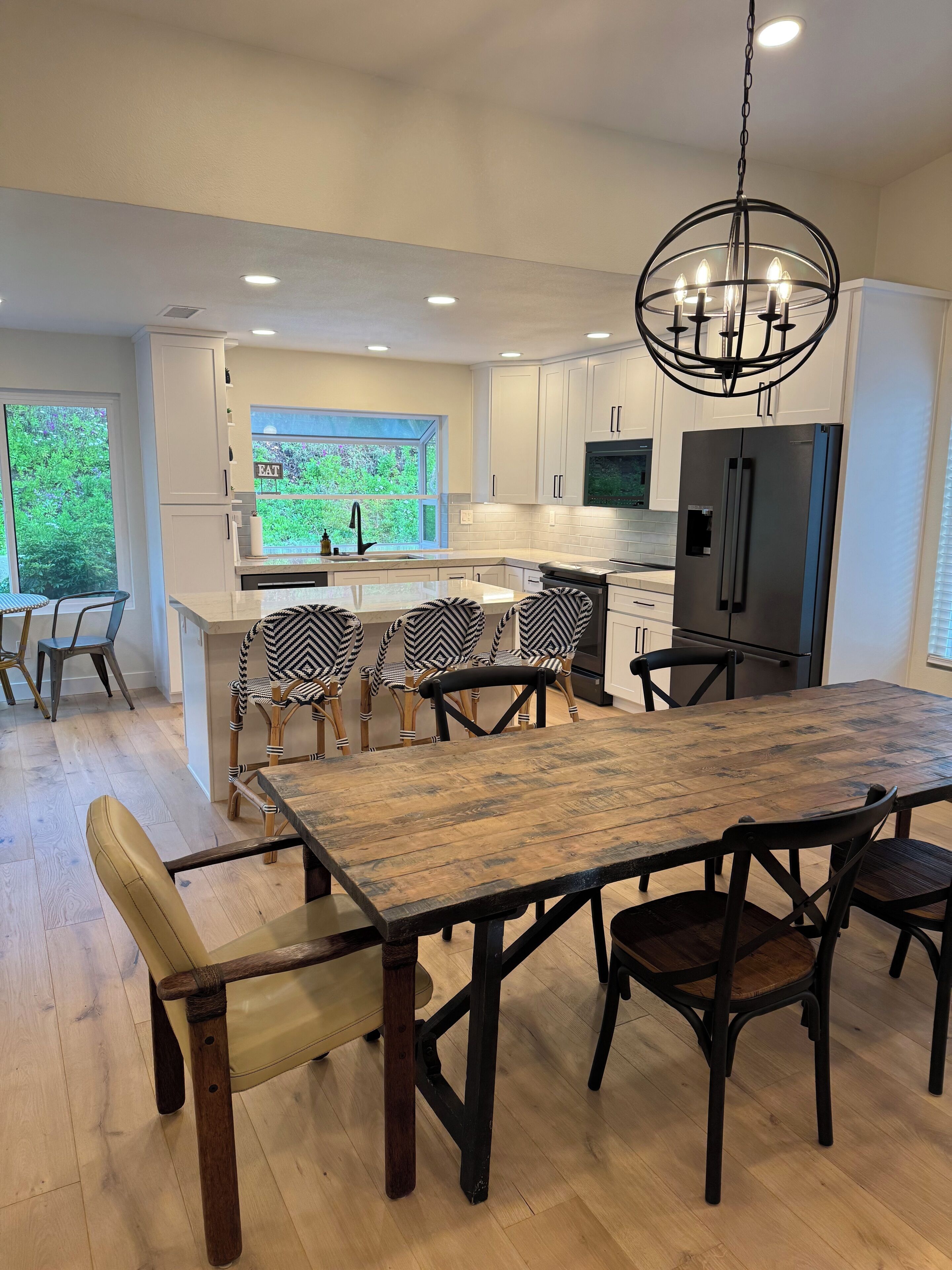 A modern kitchen with white cabinetry, a large island, a built-in oven, and a stainless steel refrigerator.