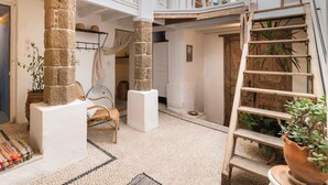 Un loft amplio con techos altos, vigas de madera a la vista y una escalera central.