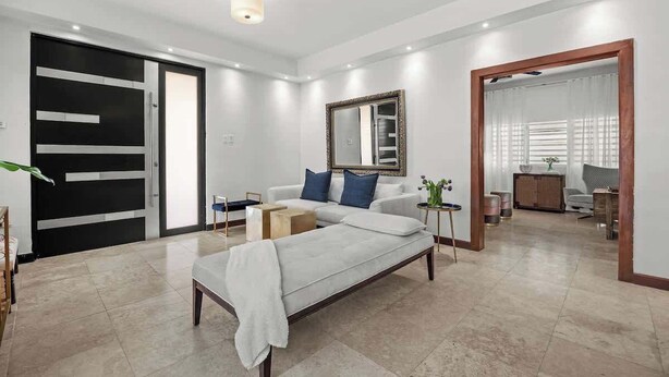 Um quarto moderno com cama, sofá, espelho e guarda-roupa.