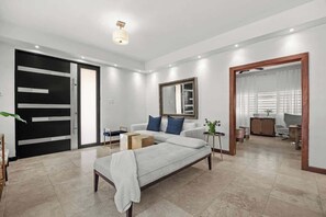 A modern bedroom with a bed, a sofa, a mirror, and a wardrobe. - Piccioni Retreat Spacious 2BR 2BA in Condado (San Juan)