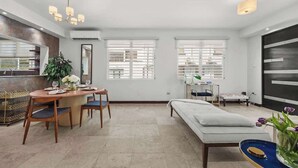 Uma sala de estar moderna com área de jantar, sofá e uma janela grande.