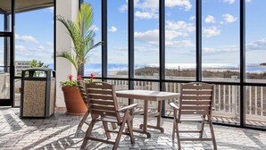 A balcony with two wooden chairs and a table, overlooking a beach with a clear sky. - 🌟Oceanfront~Awesome Amenities~ Sands Beach Club 722🌟 (Myrtle Beach)