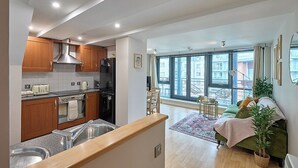Eine moderne Küche mit Edelstahlgeräten, Holzschränken und einem großen Fenster mit Blick auf die Stadt.