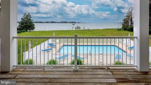 Eine überdachte Terrasse mit Blick auf einen Swimmingpool und einen See.