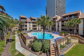 A hotel with a central swimming pool surrounded by lounge chairs and palm trees. - ☀️ Ocean Front - Prime Location - Anchorage I 107 ☀️ (Myrtle Beach)