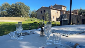 Une table dressée à l’extérieur, avec en arrière-plan un bâtiment en pierre.
