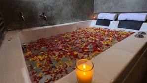 Une baignoire remplie de pétales de rose et une bougie allumée.