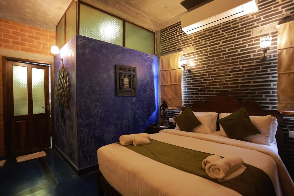 Une chambre d’hôtel avec un grand lit, une table de chevet, une lampe fixée au mur et un mur dont le motif rappelle celui d’un mur en briques.