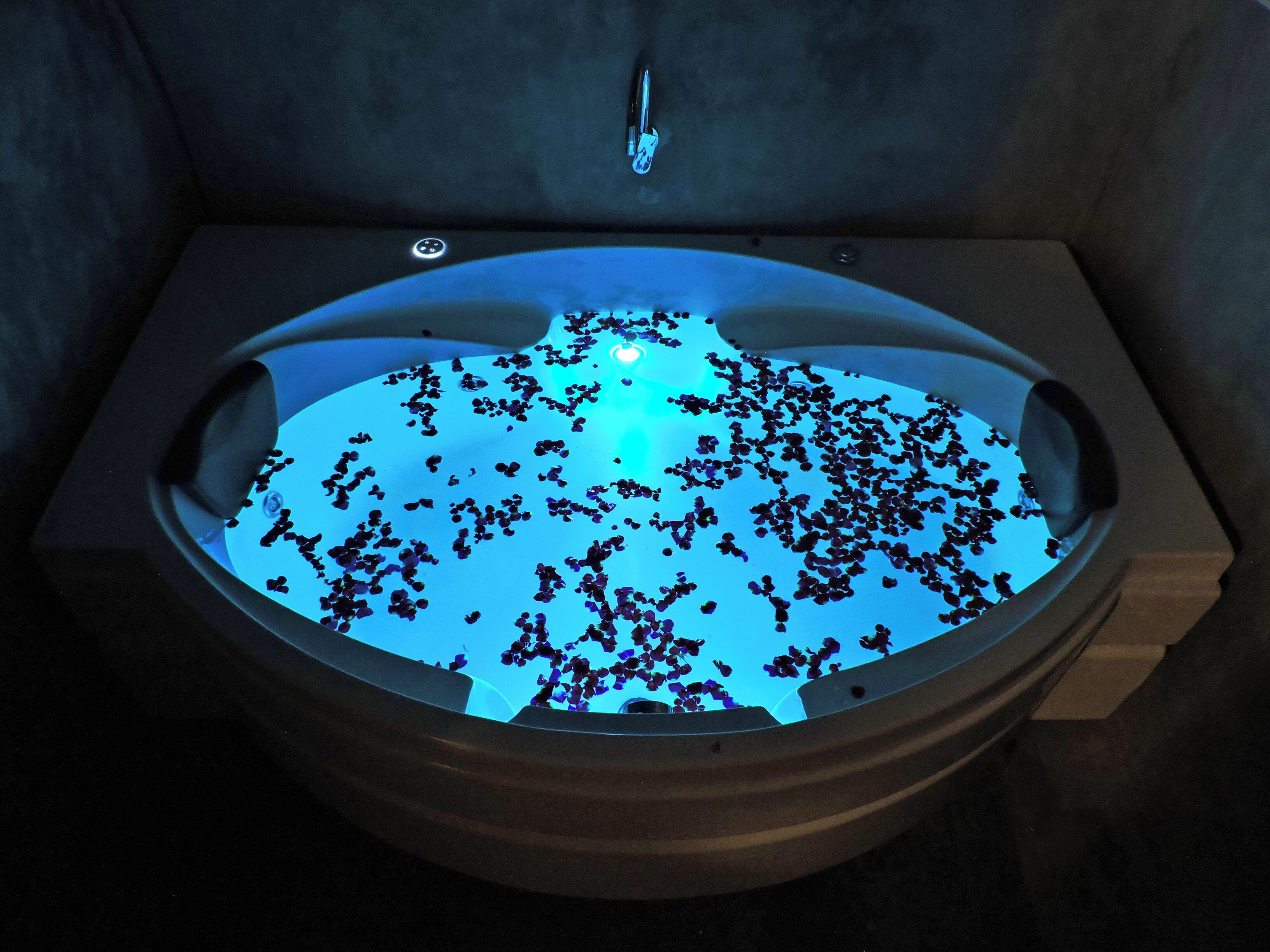 A bathtub filled with water and scattered rose petals.