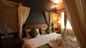 Une chambre d’hôtel avec un lit, une literie verte et blanche, une table de chevet avec une lampe et une tête de lit en bois.
